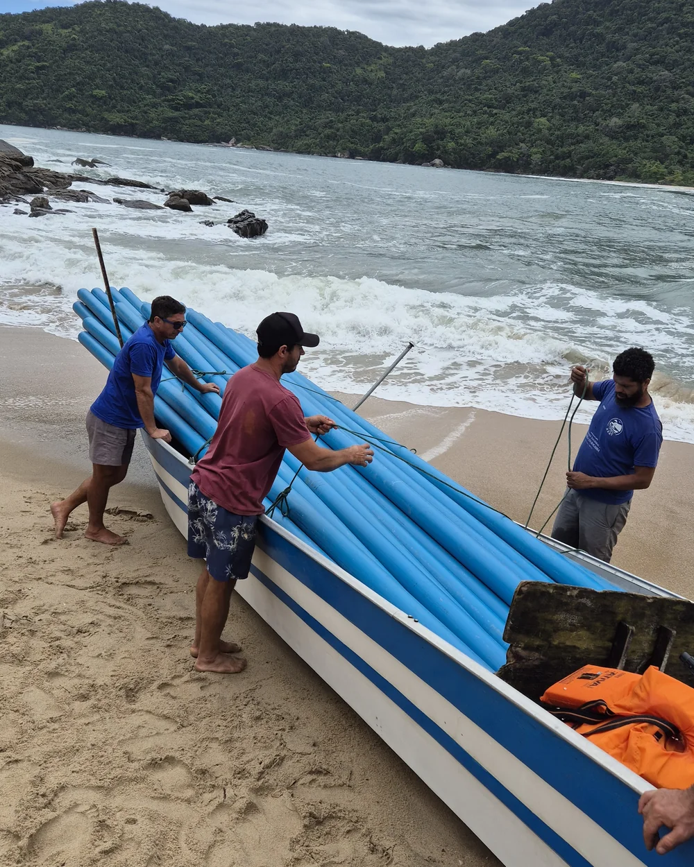 Equipe transportando tubulações por barco